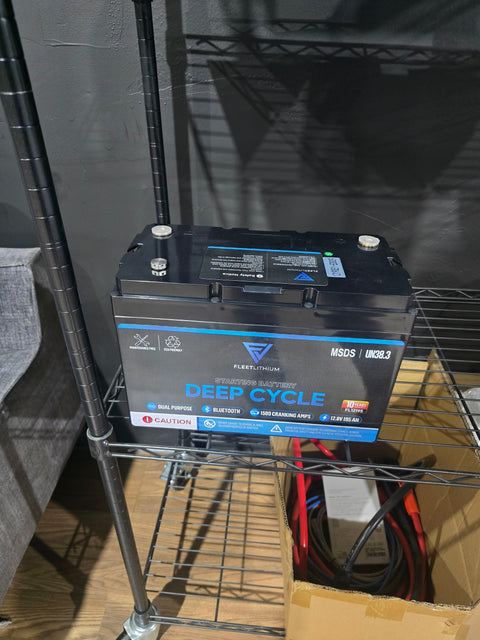 Real Fleet Lithium 12.8V 195Ah deep cycle battery, model FL12195, photographed on a shelf; label shows Bluetooth and 10-year warranty.