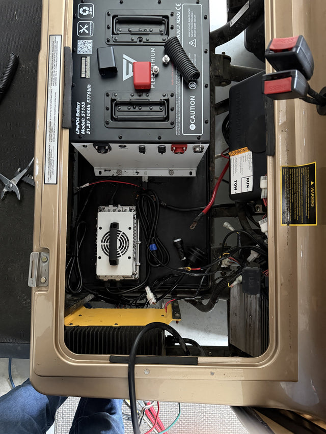 Fleet 51105 51.2V 105Ah battery and charger positioned in a Tomberlin during installation; power cables remain disconnected